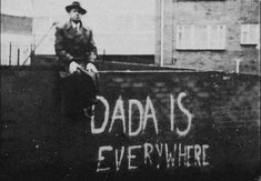 a man sitting on the side of a building with graffiti written on it's wall