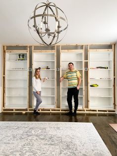 a man and woman standing in front of open bookcases with shelves on each side