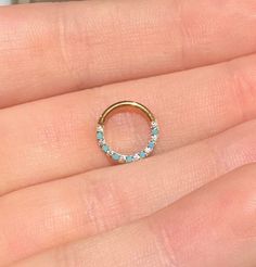 a woman's hand holding a gold ring with blue stones on it and a diamond band