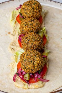 three falafes on a tortilla with lettuce and tomatoes