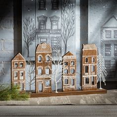 three wooden houses with trees and snow on the ground in front of a christmas scene