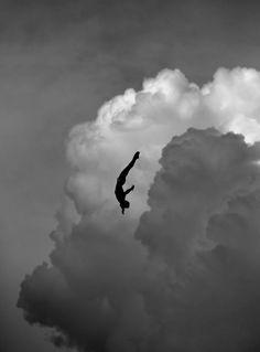 a person in the air with their feet up and arms out, while they are flying through the cloudy sky