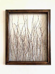 a frame with branches in it hanging on the wall