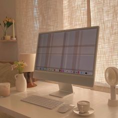 a computer monitor sitting on top of a desk next to a cup and saucer