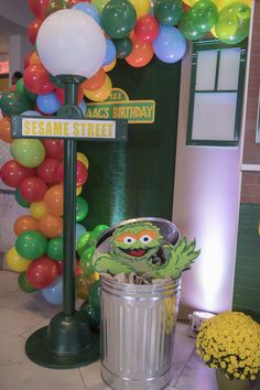 a sesame street sign next to a trash can with balloons in the shape of animals