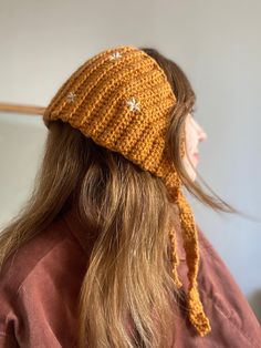 a woman with long hair wearing a yellow knitted headband and stars on it