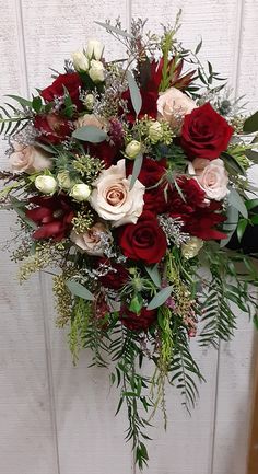 a bouquet of red and white flowers is hanging on a door handle with greenery