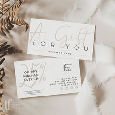 two business cards sitting next to each other on top of a white cloth covered table