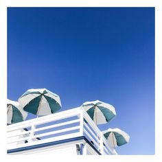 several umbrellas are set up on the top of a building under a blue sky