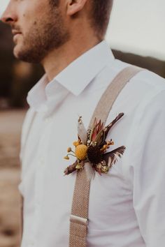 a man wearing a white shirt and suspenders with a flower on his lapel