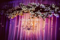 a chandelier hanging from the ceiling in front of a purple and white backdrop