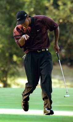 a man in maroon shirt and black pants playing golf