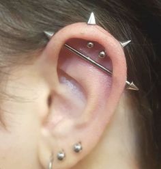 an ear with three different piercings on it's sides and one is in the middle