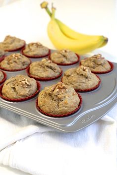 muffins are sitting on a baking tray next to a banana