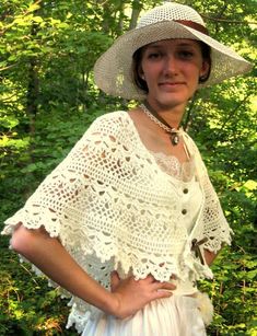 a woman wearing a white hat standing in front of some trees with her hands on her hips