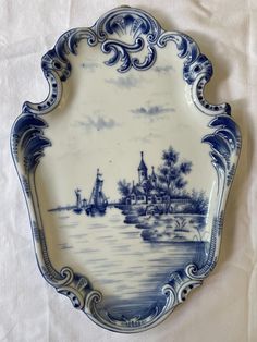 a blue and white plate sitting on top of a cloth covered table next to a wall