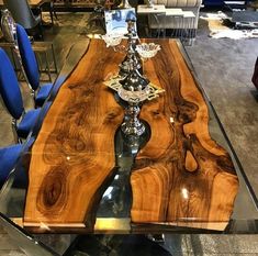 a table made out of wood and glass with blue chairs in the backround