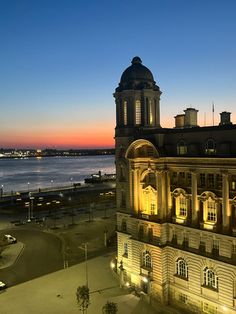 an old building is lit up at night by the water