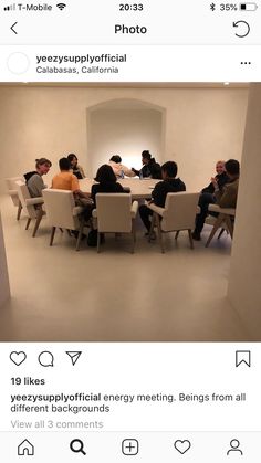 a group of people sitting at a table in a room with white walls and chairs