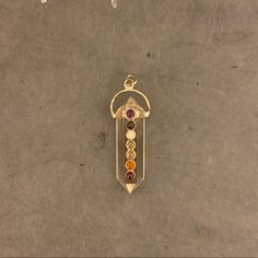 a gold pendant with five stones hanging from it's side on a concrete surface