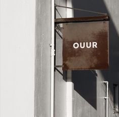 a sign hanging from the side of a building that says ouur in white letters