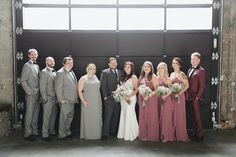 a group of people standing next to each other in front of a garage door wearing suits and ties