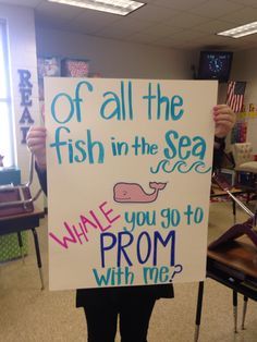 a person holding up a sign that says, of all the fish in the sea whale you go to prom with me?