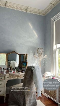 a bedroom with blue walls and furniture in the room, including a dressing table that has a mirror on it