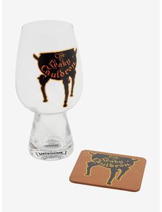 a glass and coaster sitting next to each other on a white surface with an image of a cow