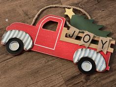 a wooden toy truck with a christmas tree on the back and name joy hanging from it