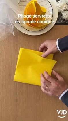 a person cutting paper on top of a wooden table next to a plate and bowl