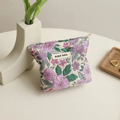 Timeless Elegance and Practicality Embrace the charm of vintage style with our Vintage Floral Cosmetic Bag. This beautifully designed cosmetic bag features an elegant purple flower pattern that adds a touch of sophistication to your everyday essentials. Whether you're heading to work, a weekend getaway, or a night out, this compact and stylish bag is your perfect companion. Perfect for Every Occasion Our Vintage Floral Cosmetic Bag is designed for versatility. Its small size makes it ideal for fitting into your handbag or luggage, ensuring you have your beauty essentials and more within reach wherever you go. Use it as a cosmetic bag, a coin purse, or even a commuter card holder. It's perfect for those who love to keep their items organized in style. High-Quality and Durable Crafted from p Purple Portable Cosmetic Bag For Travel, Feminine Travel Cosmetic Pouch Bag, Purple Pouch Cosmetic Bag For Travel, Purple Zipper Pouch Cosmetic Bag For Travel, Purple Coin Purse With Zipper For Daily Use, Feminine Bags With Zipper Pouch For Daily Use, Daily Use Purple Pouch Coin Purse, Portable Purple Rectangular Pouch, Portable Rectangular Purple Pouch