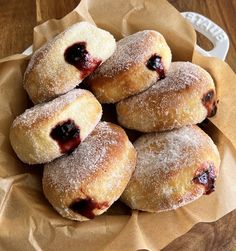 powdered sugar covered donuts with blueberries in a basket on a wooden table