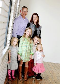 a group of people standing next to each other on top of a wooden floor in front of a white wall