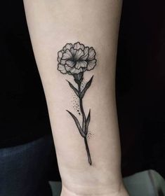 a single flower tattoo on the wrist is shown in black and grey ink, with tiny dots