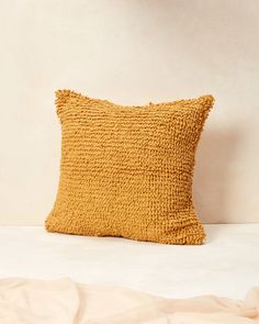 a yellow pillow sitting on top of a bed