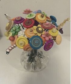 a vase filled with lots of different colored buttons and pins on top of a table