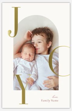 a young boy is holding his baby in front of the word joy on a white background