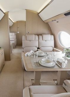 the inside of an airplane with tables, chairs and couches on each side of the plane