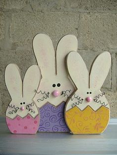 three wooden bunnies with faces painted on them