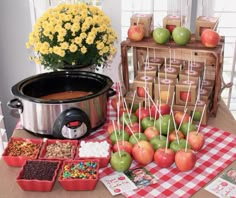 an assortment of apples and candies on a table next to a crock pot