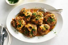 a white plate topped with meatballs covered in sauce and garnished with parsley