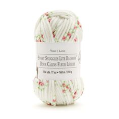 the yarn ball is white and has pink flowers on it, with green trimmings