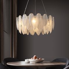 a chandelier hanging over a dining room table with chairs and plates on it