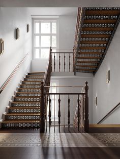 the stairs are made of wood and have decorative railings on each side, along with an iron handrail