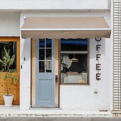 a store front with an awning and potted plants in the window sill