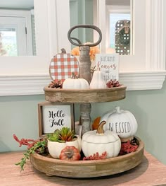 three tiered tray filled with pumpkins and other decorations