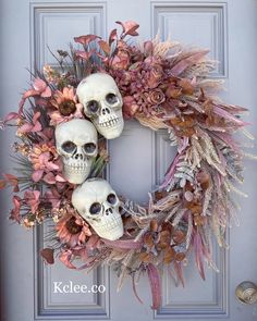 a wreath with three skulls and flowers on the front door, decorated with dried leaves