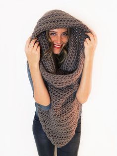 a woman wearing a knitted shawl with her hands on her head and looking at the camera