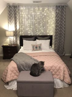 a cat sitting on top of a foot stool in a bedroom with lights behind the bed